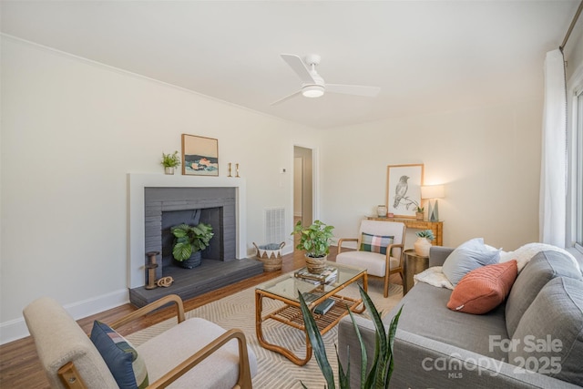 living room with ceiling fan, wood-type flooring, and a fireplace