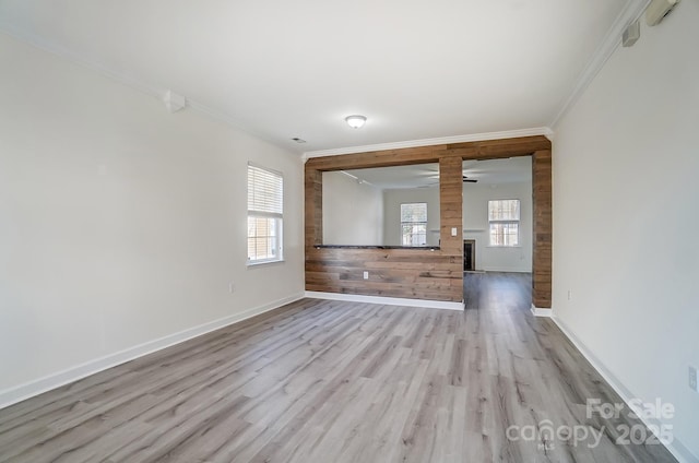 empty room with ceiling fan, light wood-type flooring, and crown molding