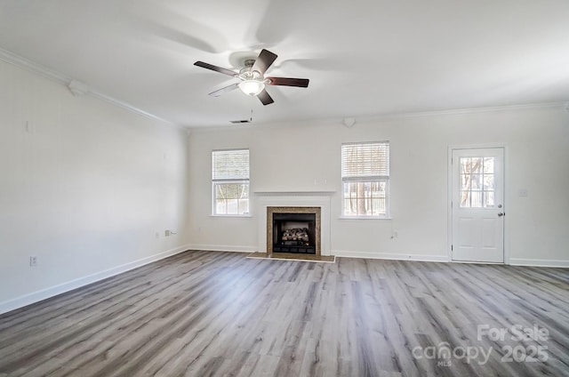 unfurnished living room with ceiling fan, plenty of natural light, ornamental molding, and light hardwood / wood-style flooring