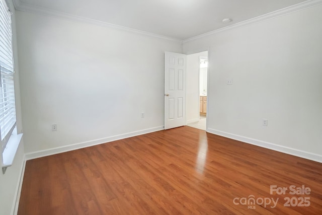 empty room featuring wood-type flooring and ornamental molding