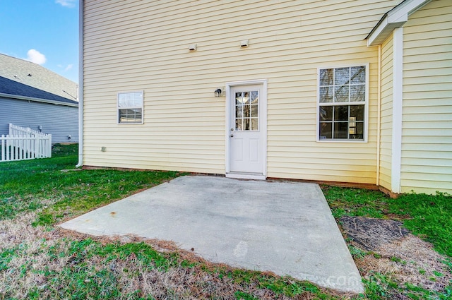 view of exterior entry featuring a yard and a patio