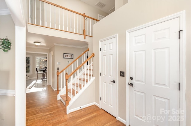 foyer with light hardwood / wood-style floors and crown molding