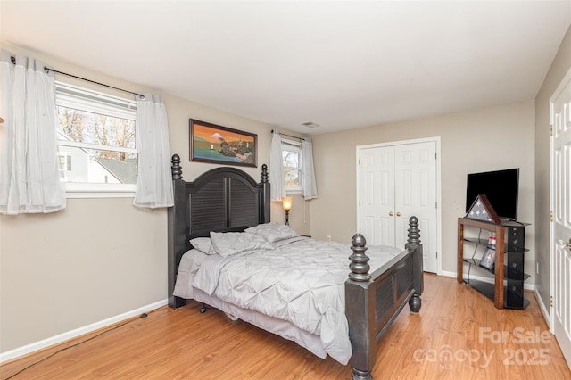 bedroom featuring multiple windows, a closet, and light hardwood / wood-style floors