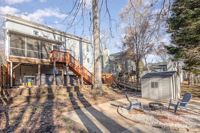 rear view of property with a deck, a storage shed, an outdoor fire pit, a patio area, and a sunroom