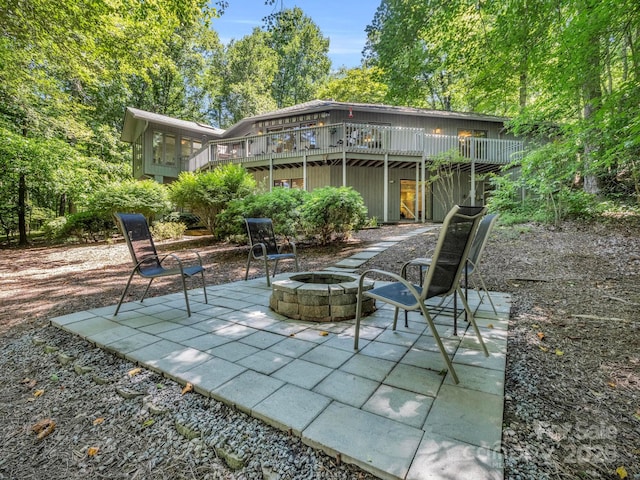 view of patio / terrace featuring a sunroom, a fire pit, and a wooden deck