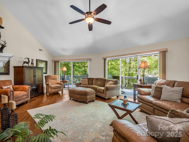 living room with hardwood / wood-style floors, ceiling fan, and high vaulted ceiling