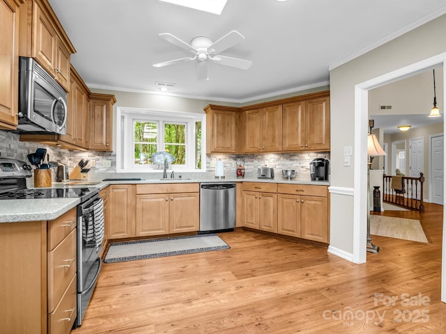 kitchen with crown molding, sink, stainless steel appliances, and light hardwood / wood-style flooring