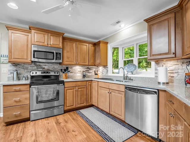 kitchen featuring light stone countertops, backsplash, stainless steel appliances, and crown molding