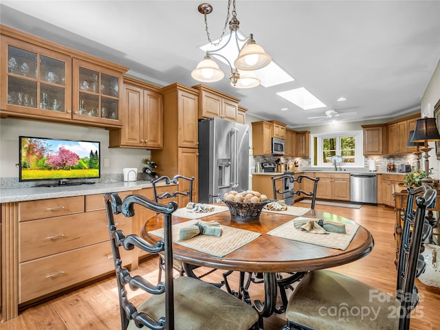 dining room featuring a chandelier, light hardwood / wood-style flooring, and a skylight