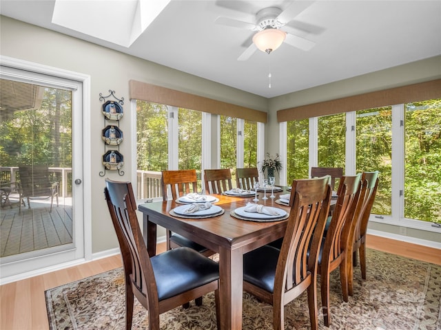 dining room featuring a skylight, ceiling fan, and hardwood / wood-style flooring