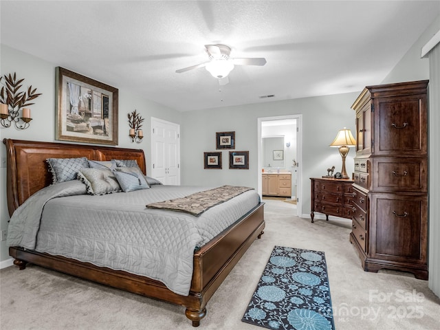 carpeted bedroom featuring ceiling fan, a textured ceiling, and ensuite bath