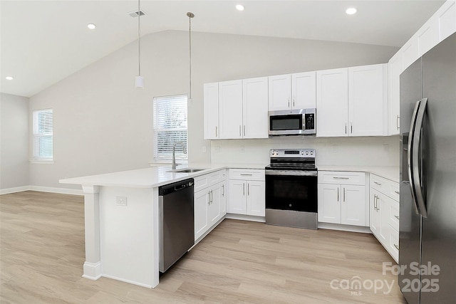 kitchen with appliances with stainless steel finishes, decorative light fixtures, white cabinetry, sink, and kitchen peninsula