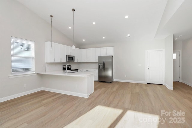 kitchen featuring sink, appliances with stainless steel finishes, hanging light fixtures, light hardwood / wood-style floors, and white cabinets