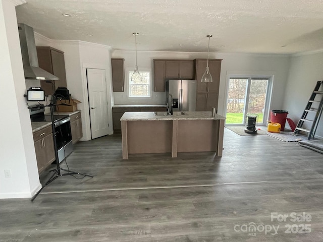 kitchen with wall chimney exhaust hood, hanging light fixtures, black electric range, stainless steel fridge, and a center island with sink