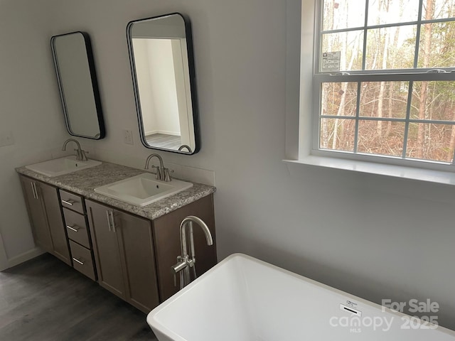 bathroom with a tub to relax in, plenty of natural light, vanity, and hardwood / wood-style flooring