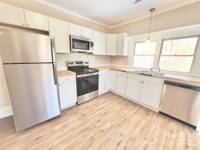 kitchen with sink, hanging light fixtures, light wood-type flooring, white cabinetry, and stainless steel appliances