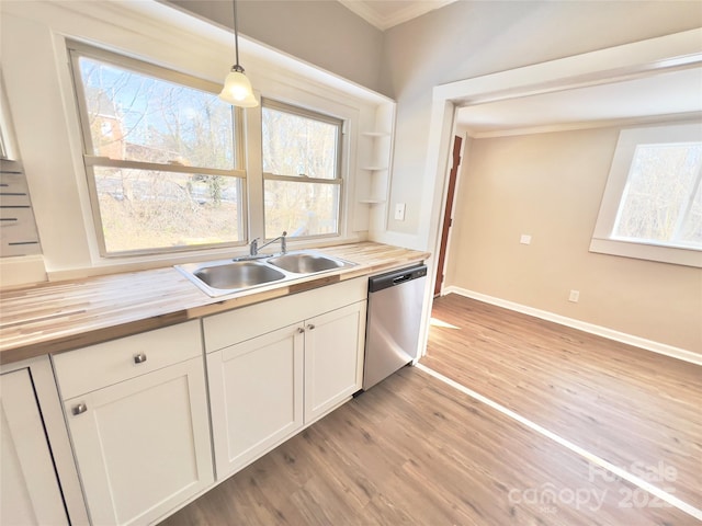 kitchen with pendant lighting, dishwasher, sink, butcher block countertops, and white cabinetry