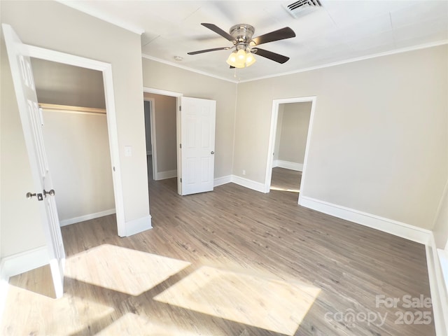 unfurnished bedroom with ceiling fan, wood-type flooring, ornamental molding, and a closet