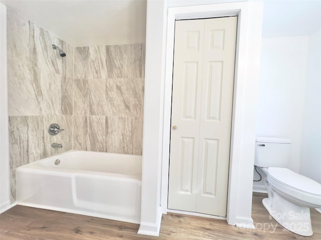 bathroom with wood-type flooring, tiled shower / bath combo, and toilet