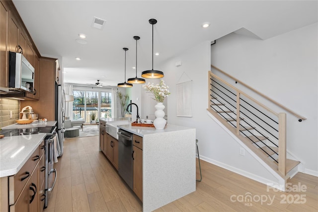 kitchen featuring appliances with stainless steel finishes, visible vents, a sink, and light wood finished floors