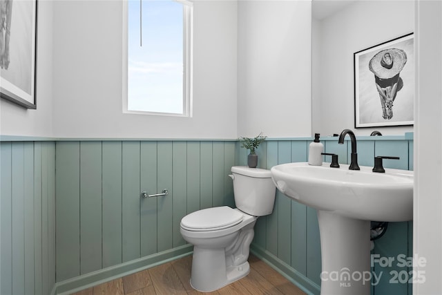 bathroom with a wainscoted wall, a sink, wood finished floors, and toilet