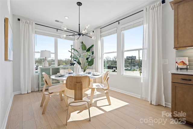 dining space with light wood finished floors, baseboards, visible vents, and a notable chandelier