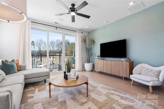 living area with light wood-type flooring, visible vents, ceiling fan, and recessed lighting