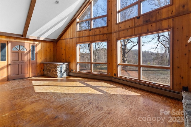 interior space featuring beamed ceiling, high vaulted ceiling, and wooden walls