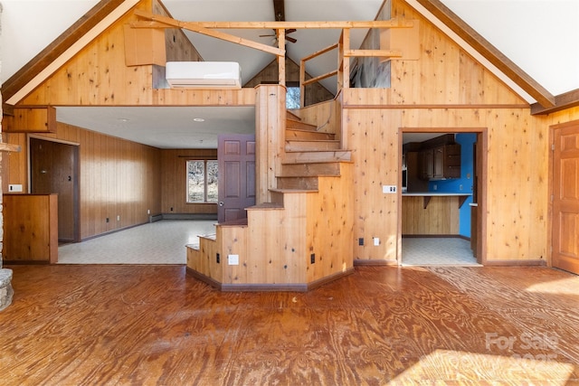 unfurnished living room with an AC wall unit, vaulted ceiling with beams, and wood-type flooring