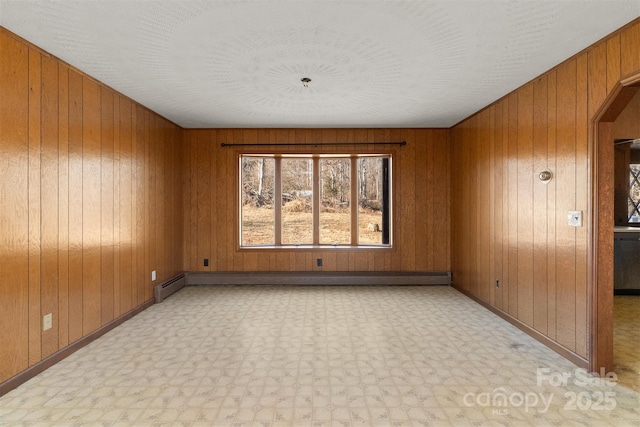 unfurnished room featuring a baseboard radiator and wooden walls