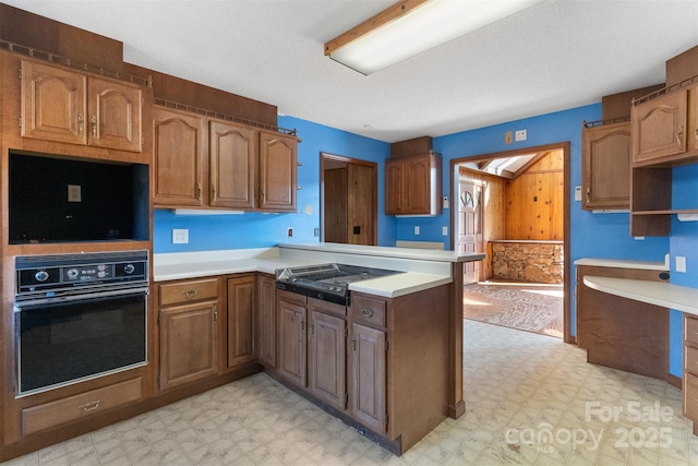 kitchen featuring cooktop, kitchen peninsula, and oven