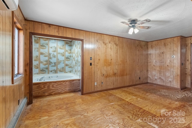 spare room with a wall mounted air conditioner, ceiling fan, a textured ceiling, and wooden walls