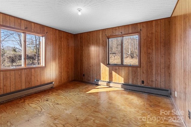 spare room featuring wooden walls and a baseboard radiator