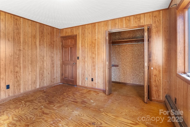 unfurnished bedroom with a closet, baseboard heating, and ornamental molding