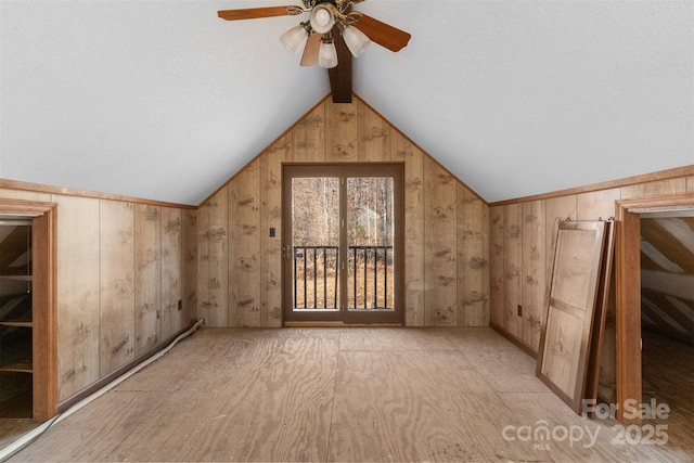 bonus room featuring wood walls, vaulted ceiling with beams, ceiling fan, and light hardwood / wood-style flooring