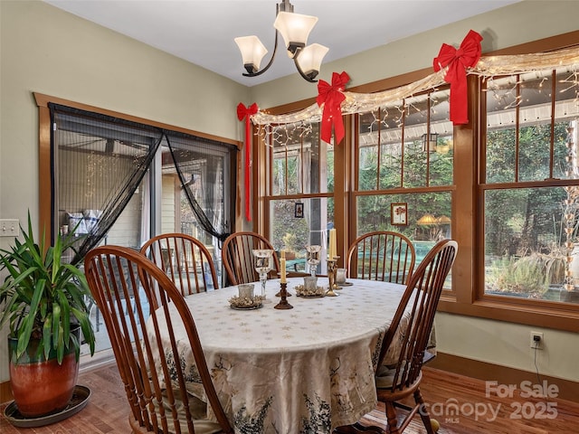 dining room with hardwood / wood-style floors, plenty of natural light, and an inviting chandelier