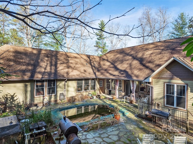 rear view of house featuring a patio and roof with shingles