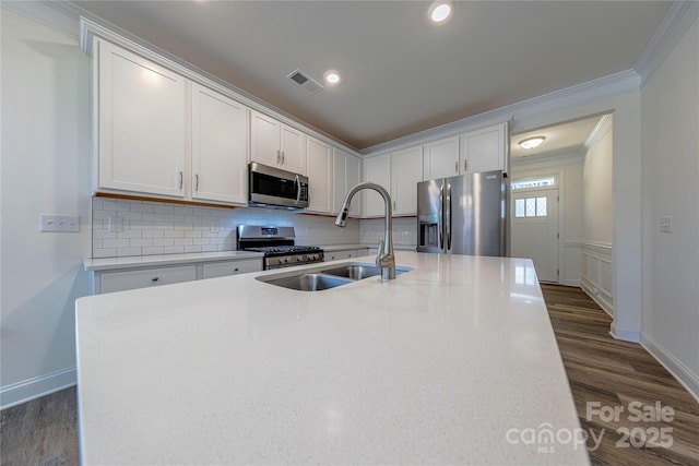 kitchen featuring sink, stainless steel appliances, a kitchen island with sink, white cabinets, and ornamental molding