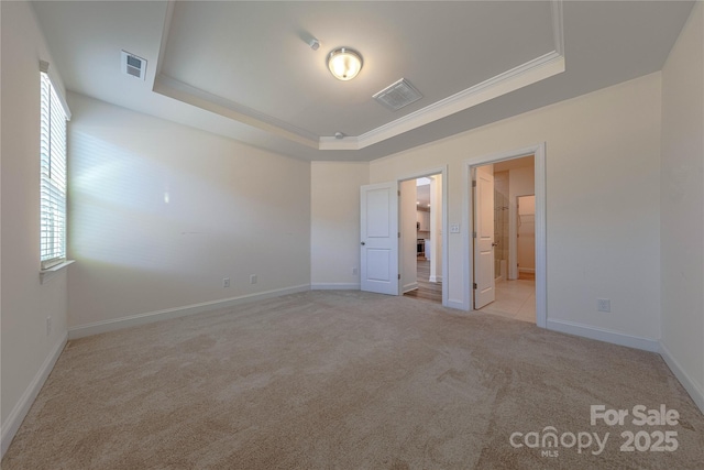 unfurnished bedroom with light carpet, connected bathroom, a tray ceiling, and crown molding