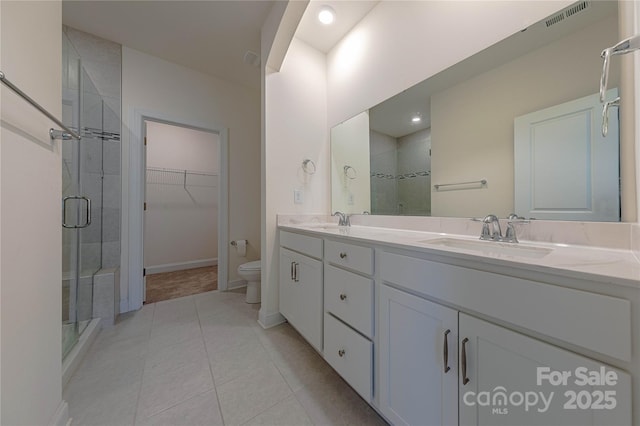 bathroom with tile patterned floors, vanity, toilet, and a shower with shower door