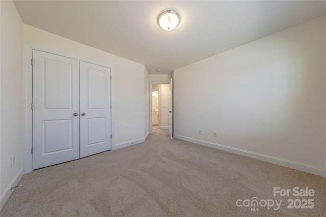 unfurnished bedroom with light colored carpet and a closet