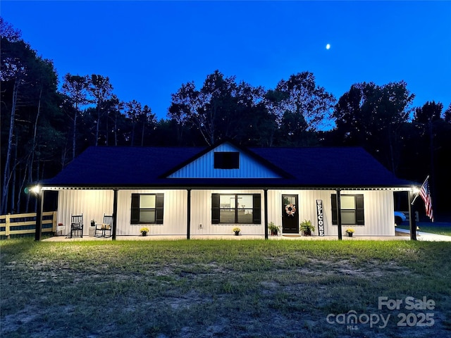 modern farmhouse with fence, a front yard, and board and batten siding
