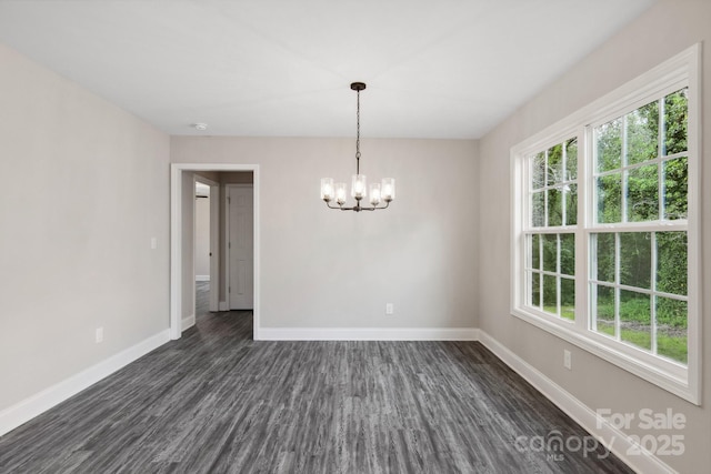 unfurnished room with dark hardwood / wood-style flooring, a wealth of natural light, and an inviting chandelier