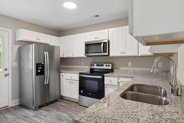 kitchen featuring light stone countertops, appliances with stainless steel finishes, sink, and white cabinets