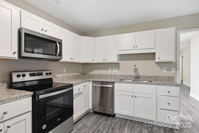 kitchen with dark hardwood / wood-style floors, white cabinetry, sink, light stone counters, and stainless steel appliances