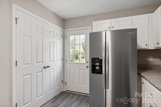 kitchen with stainless steel refrigerator with ice dispenser, white cabinetry, stone countertops, and dark hardwood / wood-style floors