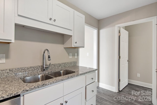 kitchen with white cabinetry, dark hardwood / wood-style flooring, sink, and light stone counters