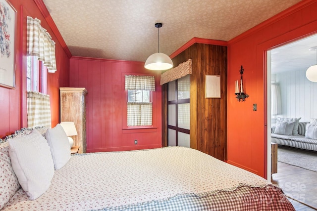 bedroom with ornamental molding, a textured ceiling, and wood walls