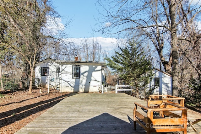 back of property featuring a storage unit and a deck