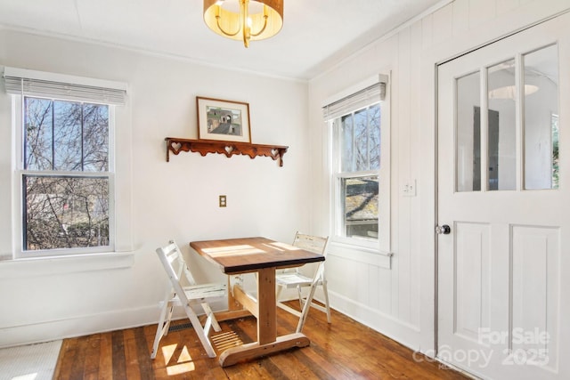 dining space with dark wood-type flooring, ornamental molding, plenty of natural light, and a chandelier